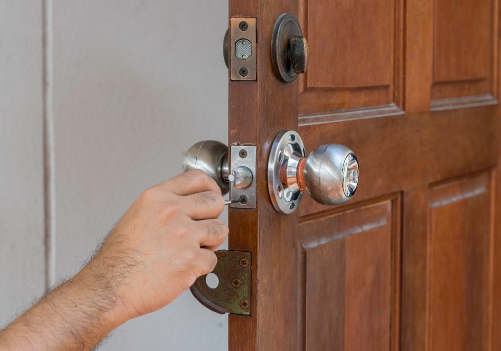 Hand opent voorzichtig een houten deur met een metalen deurknop zonder schade.