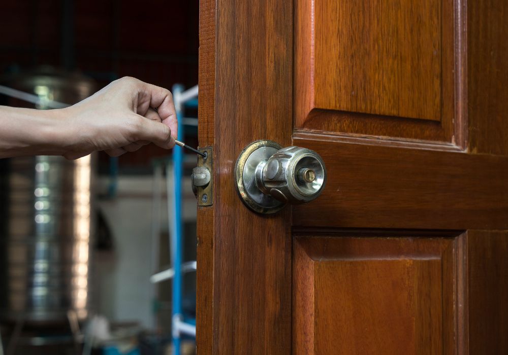 Hand van een slotenmaker die een houten deur opent met speciaal gereedschap.