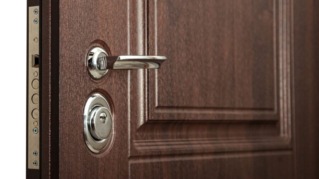 Close-up van een moderne houten deur met een chromen deurklink en een meerpuntssluiting.