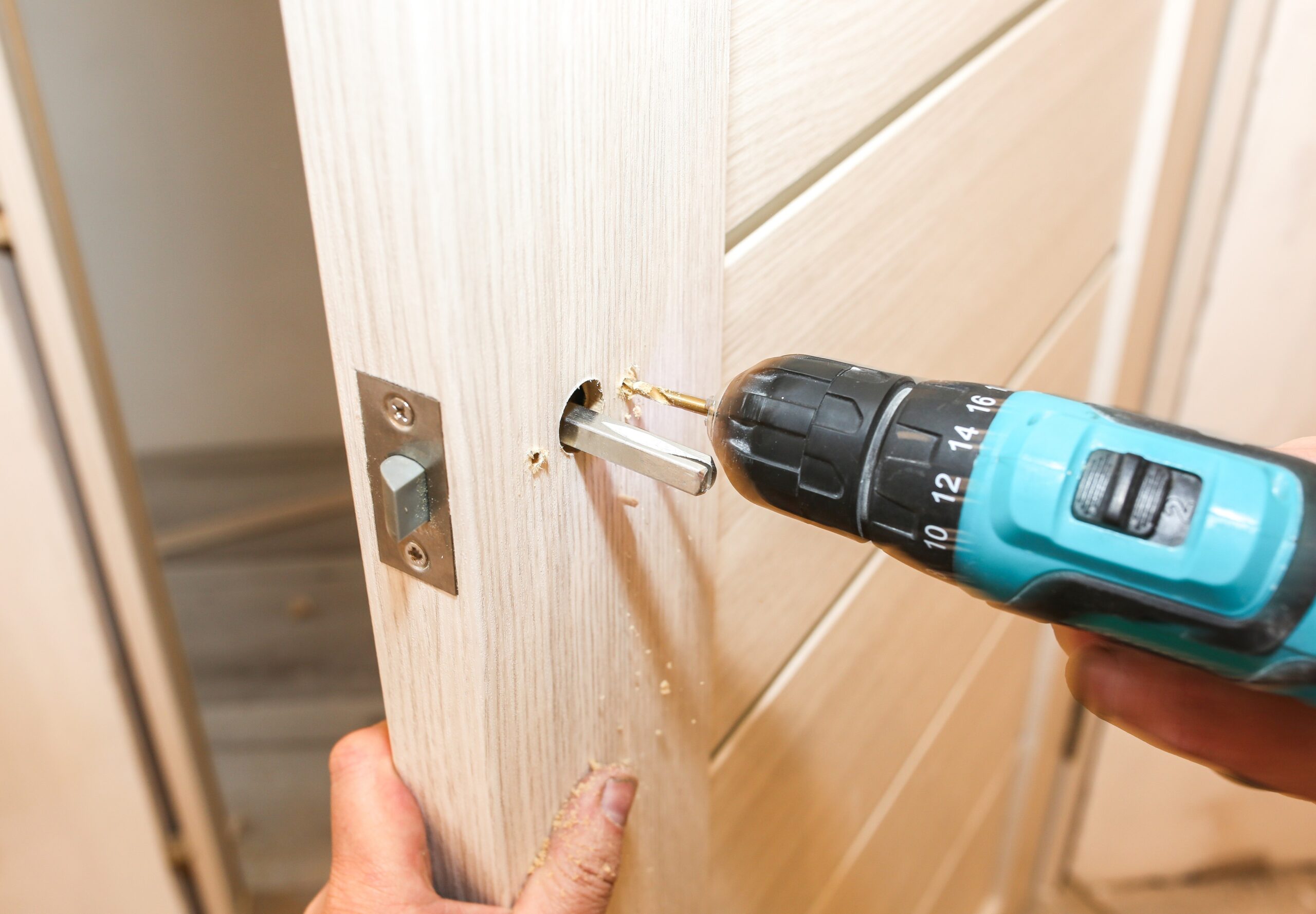 Installeren van een deurslot met een elektrische boor op een houten deur